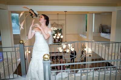 bride tossing bouquet over the railing above the grand room
