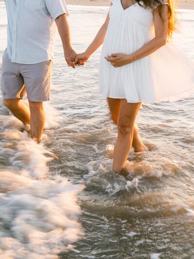 Couple holding hands wading in ocean