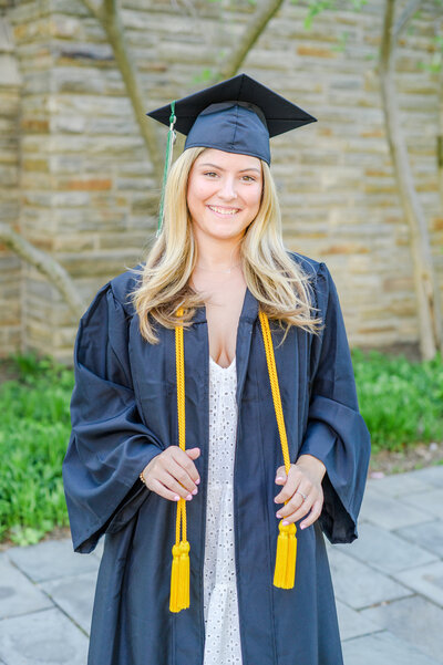 Loyola Maryland University grad poses in cap and gown in front of Loyola chapel during Baltimore graduation session