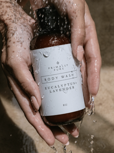 Hands holding a bottle of Primally Pure Body Wash