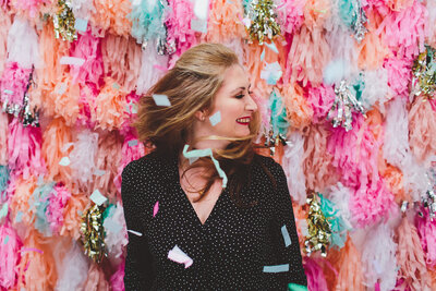 Samantha Ball smiling facing the side with fun festive backdrop