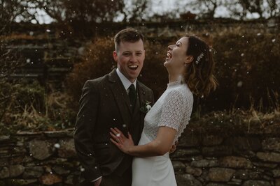 bride and groom laugh in the snow