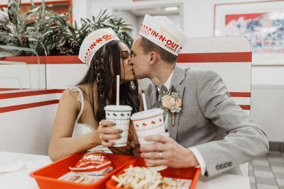 Bride and groom kiss while grabbing food on their wedding day from In-n-Out