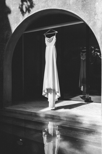 Bride's dress hung in arch way in Tulum villa.