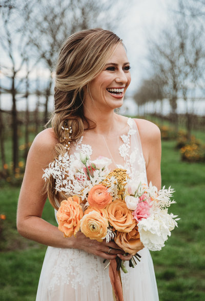 Bride smiling and holding spring bouquet at Jacuzzi Vineyard in Napa