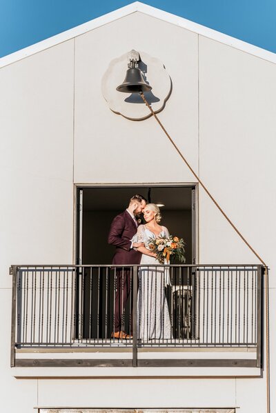 Groom embraces his bride on a balcony