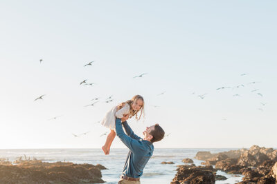Father holding daughter up in the air  at Carmel Beach