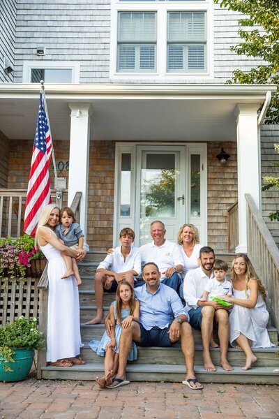 Family sitting on front porch with american flag, by new jersey family photographer
