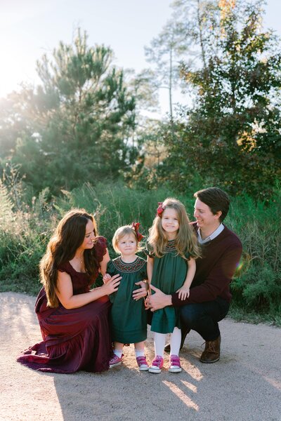 Family portrait with two young daughters in dresses, parents embracing them