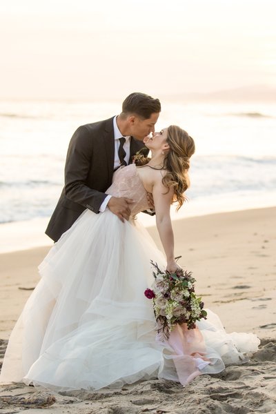Handsome groom dipping Beautiful Bride on the beach in Santa Barbara, California