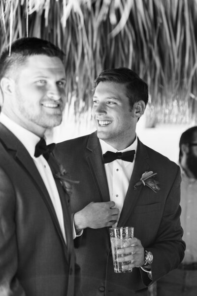 Black and white candid portrait of groomsmen laughing together