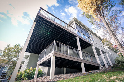 Low angle view of a two-level deck with long posts wrapped in white PVC. 