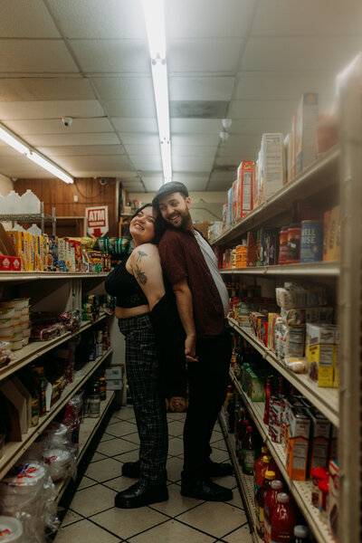 Couple stands back to back smiling in New Orleands convenience store smiling