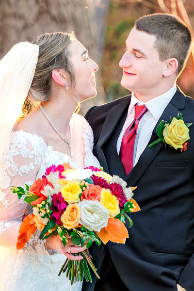 A newly wed couple smiling at each other during their fall Raleigh wedding by JoLynn Photography, a Raleigh wedding photographer