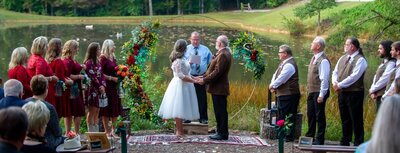 man and woman getting married by a pond