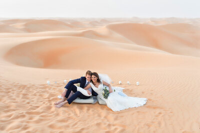 Wedding couple posing in front of sweetheart table overlooking Arabian desert dunes, photoshoot in Dubai organized by Lovely & Planned