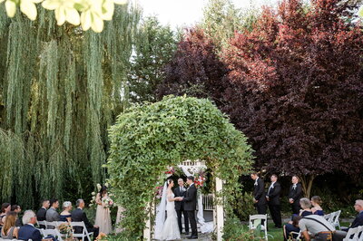 Garden wedding ceremony with willow tree and archway