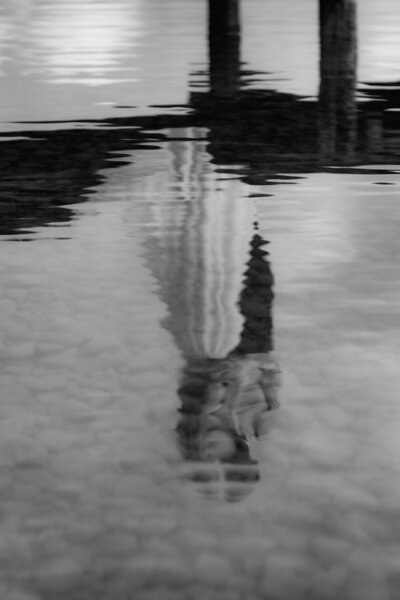 Im Wasser spiegelt sich das Abbild eines Hochzeitspaares in einer engen Umarmung.