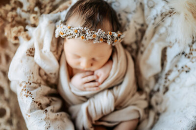 Close up photo of newborn girl wearing dired floral headband with yellow flowers