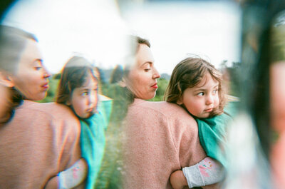 photo taken through a prism of a mom holding her young daughter while they look to the right
