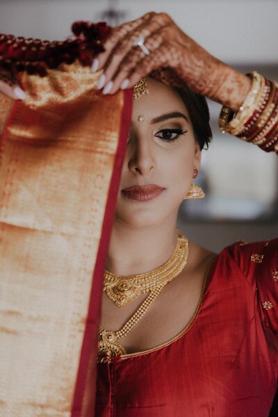 Bride wearing red with henna on hands and gold jewelry