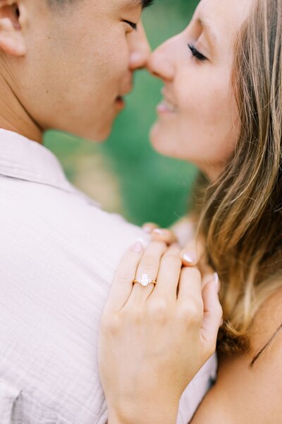 Engagement photo close up of kissing with engagement ring hand on shoulder