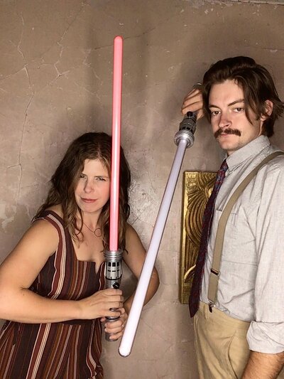 Couple using lightsabers in photo booth