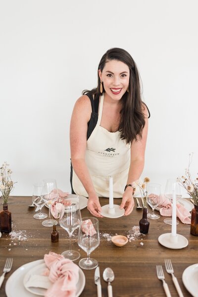Lifestyle headshot of Nashville wedding planner styling a wedding table with pink linens and Himalayan salt