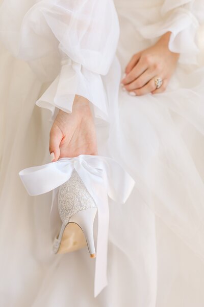 Bride holds wedding shoes