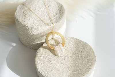 styled image of a handmade necklace displayed on round rocks and a white background