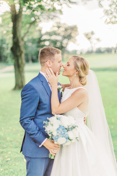 bride embraces her grooms face while going in for a kiss