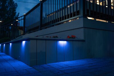 Composite built-in planters with integrated LED lights shining in blue at Adele's Frozen Custard at nighttime. 