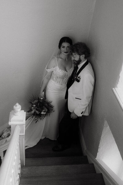 Black and white image of a father holding a mother and their young son, mother smiling at the camera, capturing authentic, emotional family moments that celebrate connection and presence