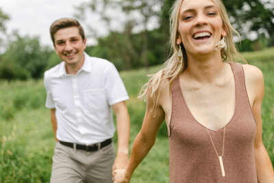 Couple laughing and running at an engagement session at Kensington Metropark
