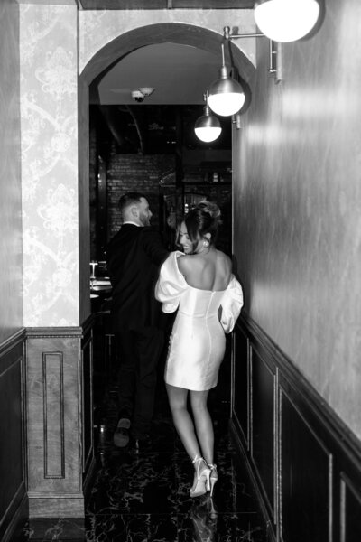 Photo of a couple running down hallway during Philly engagement session at underground bar taken by a  Philadelphia wedding photographer