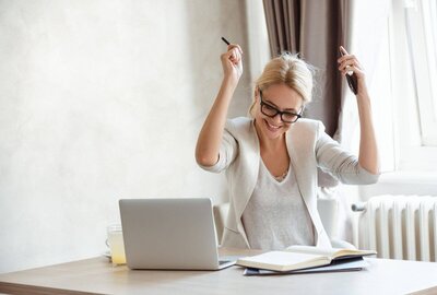 Happy woman entrepreneur celebrating in front of her laptop