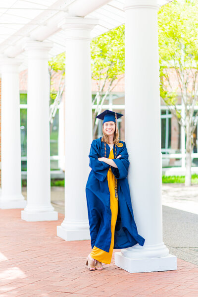 graduate in cap and gown leaning on column