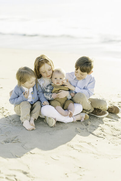 four cousins snuggling on the beach during a coastal blue and white extended family session in old orchard beach maine by carrie pellerin