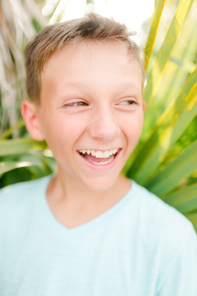 A teenage boy laughing during a family photo session on Honeymoon Island in Florida.