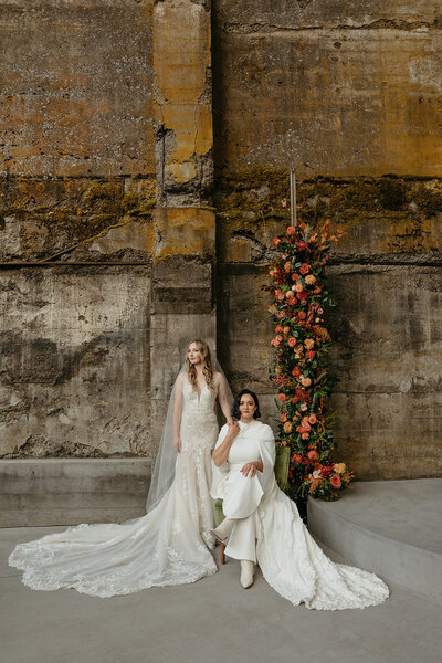 Couple Together in Front of Floral Backdrop - Megan & Amber | The Ruins PNW Inspired Wedding Hood River Oregon – LGBTQ