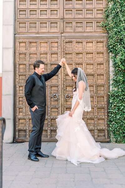 Groom twirling bride in front of large doors at the Omni resort in Scottsdale