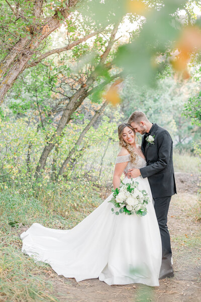 Bride and groom amongst green trees at the Pinecrest Wedding Venue in Palmer Lake, Colorado.