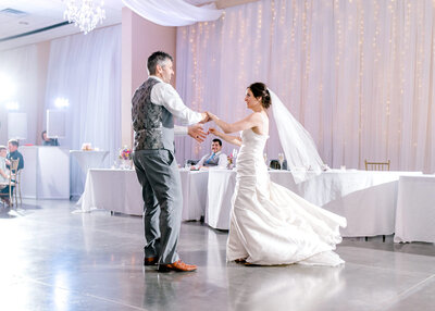 Groom twirling his bride on the dance floor at Omaha Il Pilazzo