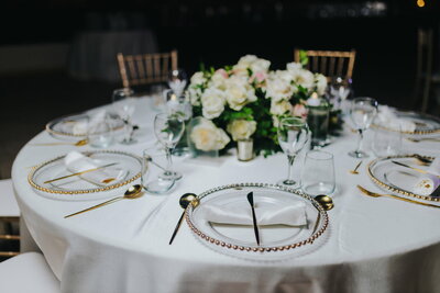 A table setting with gold and white plates and silverware.