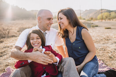 Happy family with twin toddlers sit in grass at sunset