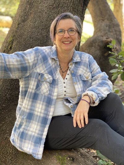 Woman smiling, sitting on a huge tree branch