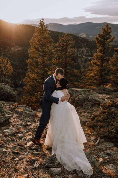 newly weds hugging on top of colorado mountain
