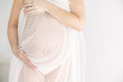 baby bump wraped in lace with moms's arms framing it