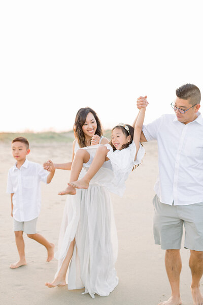 family plays in the waves as they laugh during their portrait session
