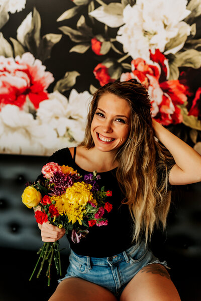 woman smiling at camera holding flowers